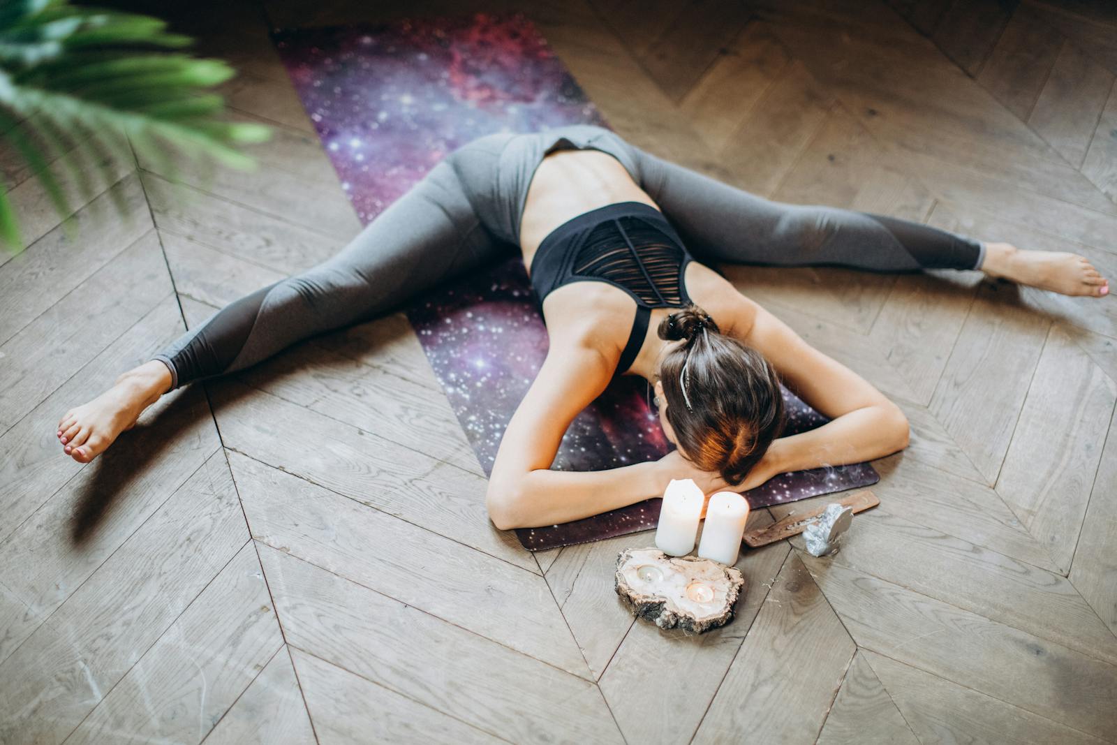 Mujer practicando yin yoga en el suelo rodeada de velas
