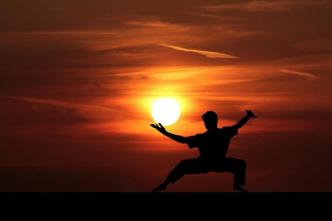 Mujer practicando la postura del guerrero (Warrior I) sobre una esterilla de yoga